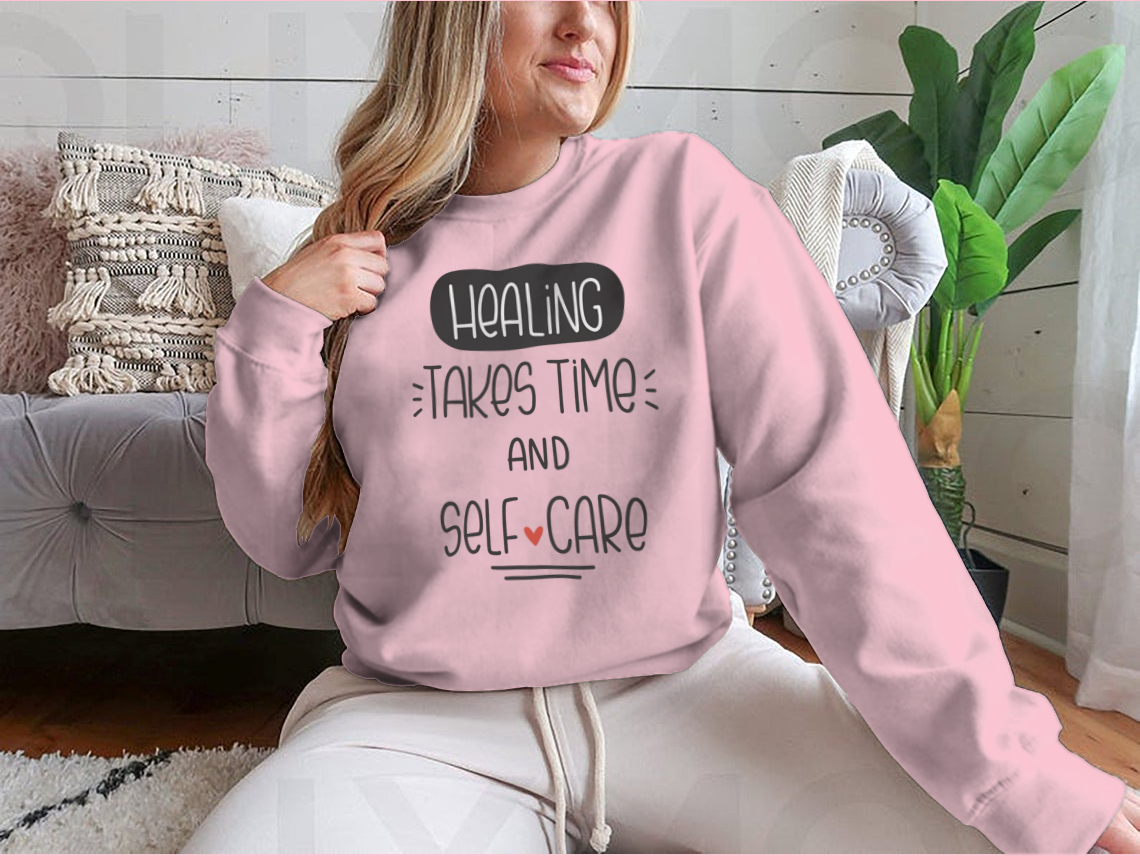 A cozy sweatshirt featuring the quote 'Healing Takes Time And Self-Care' in a stylish vector design, perfect for casual wear.