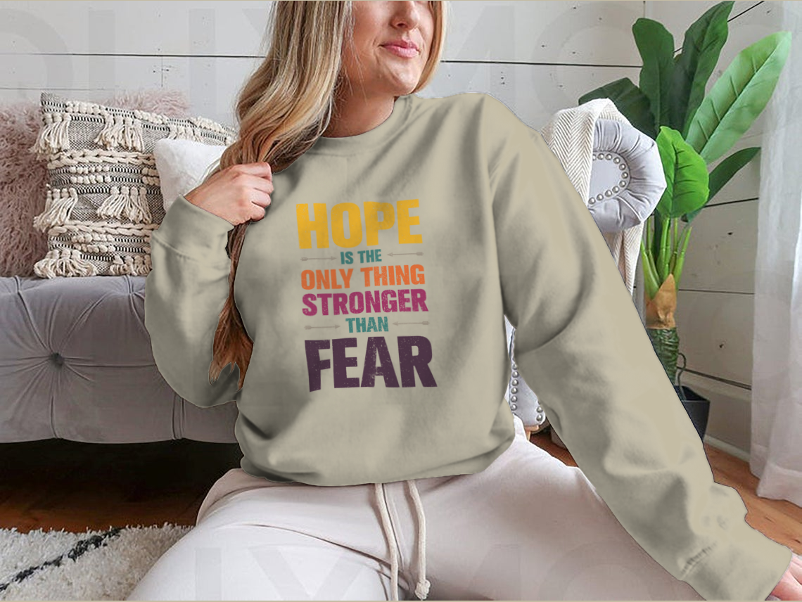 A stylish t-shirt featuring the inspirational quote 'Hope Is The Only Thing Stronger Than Fear' in a classic fit, made from a comfortable cotton-polyester blend.