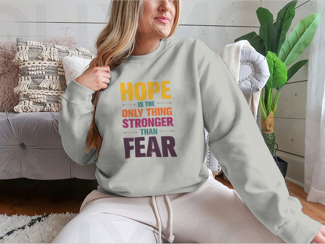 A stylish t-shirt featuring the inspirational quote 'Hope Is The Only Thing Stronger Than Fear' in a classic fit, made from a comfortable cotton-polyester blend.