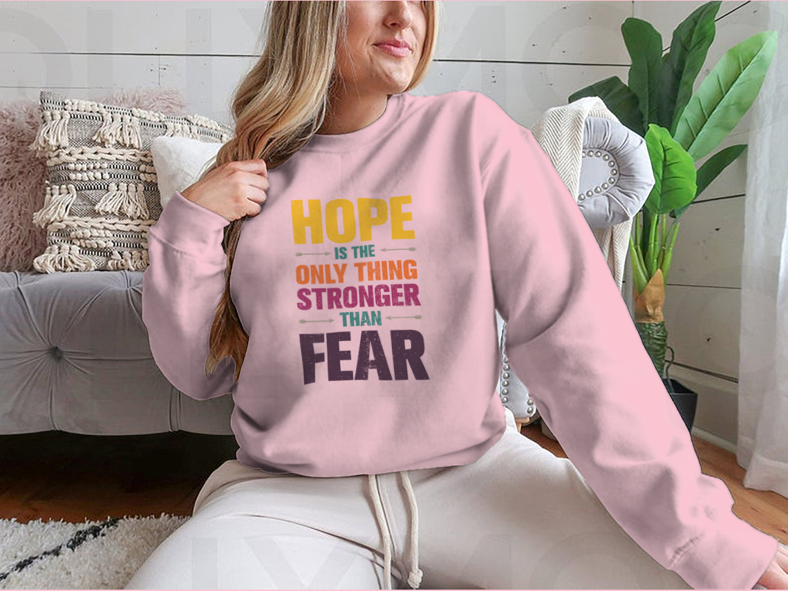 A stylish t-shirt featuring the inspirational quote 'Hope Is The Only Thing Stronger Than Fear' in a classic fit, made from a comfortable cotton-polyester blend.
