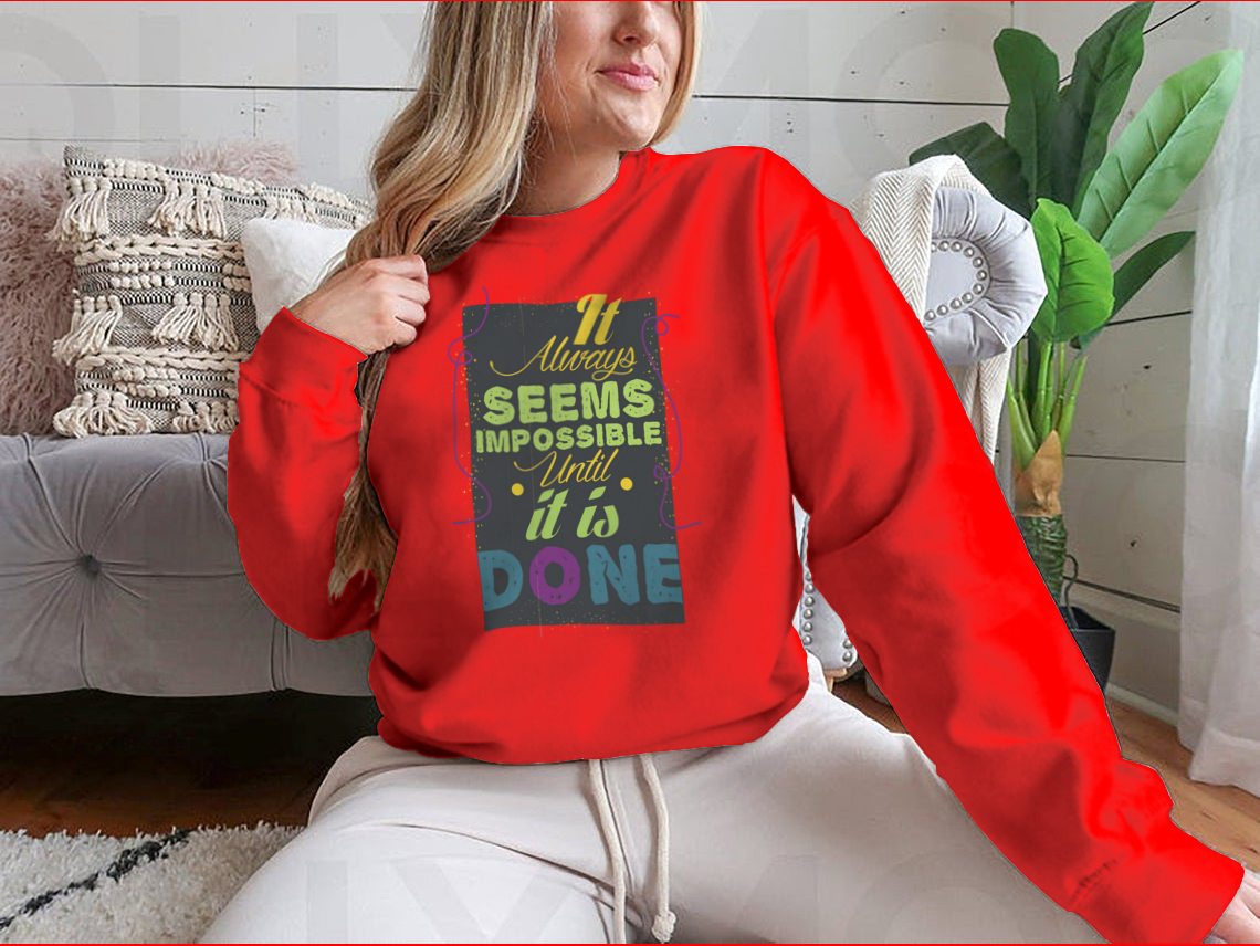 A cozy sweatshirt featuring the inspirational quote 'It Seems Impossible Until It's Done' in stylish typography, perfect for motivation.