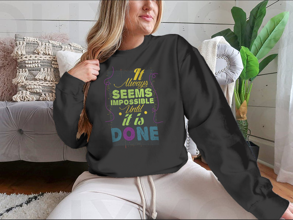 A cozy sweatshirt featuring the inspirational quote 'It Seems Impossible Until It's Done' in stylish typography, perfect for motivation.