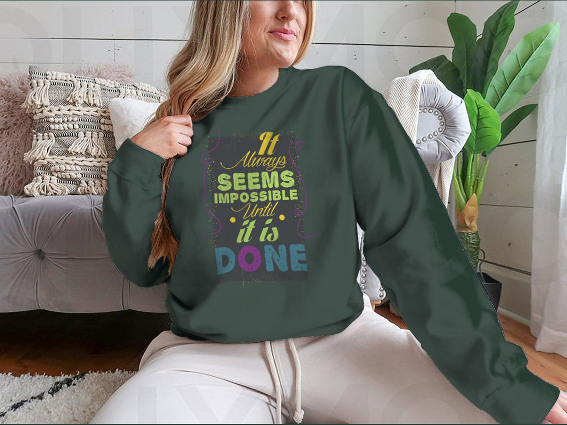 A cozy sweatshirt featuring the inspirational quote 'It Seems Impossible Until It's Done' in stylish typography, perfect for motivation.