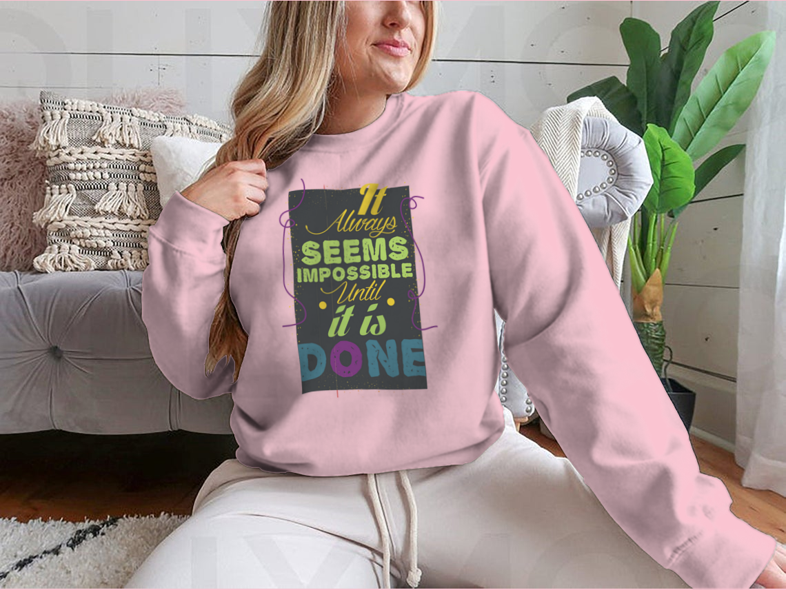 A cozy sweatshirt featuring the inspirational quote 'It Seems Impossible Until It's Done' in stylish typography, perfect for motivation.