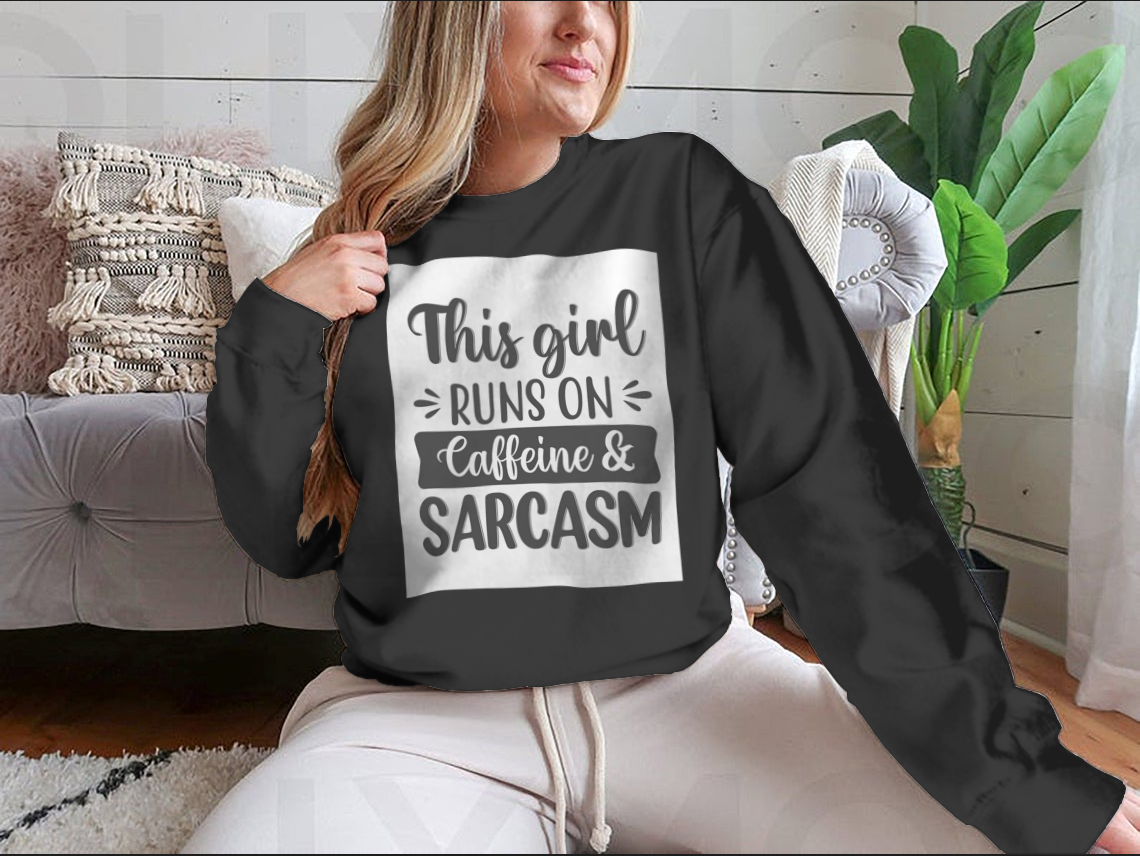 A cozy sweatshirt featuring the phrase 'This Girl Runs On Caffeine And Sarcasm' in a stylish font, perfect for coffee lovers.