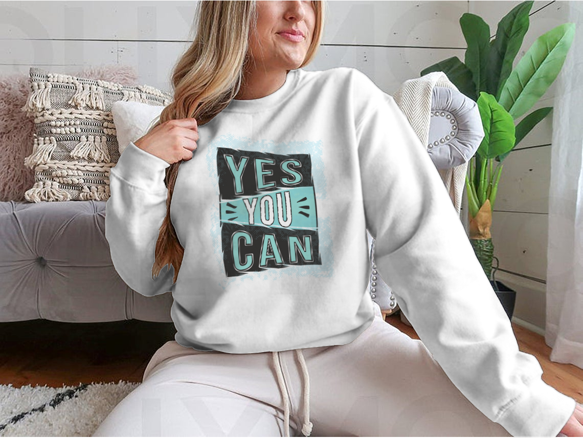 A cozy sweatshirt featuring the inspirational quote 'Yes You Can!' designed for comfort and style.