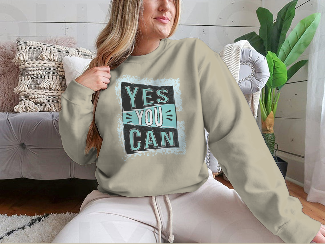 A cozy sweatshirt featuring the inspirational quote 'Yes You Can!' designed for comfort and style.