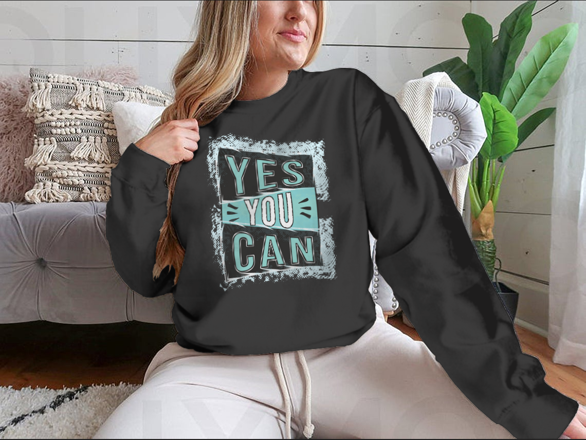 A cozy sweatshirt featuring the inspirational quote 'Yes You Can!' designed for comfort and style.