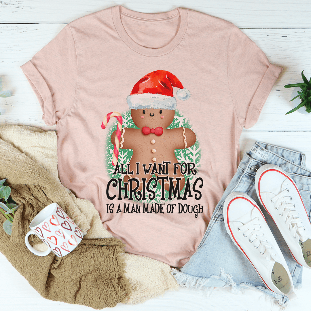 A festive Christmas-themed tee featuring the phrase 'All I Want For Christmas Is A Man Made Of Dough', made from 100% soft cotton.