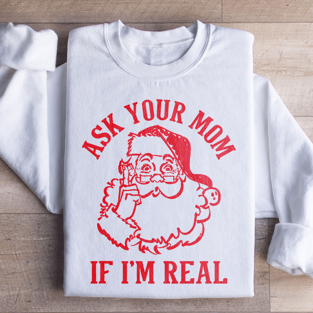 A cozy sweatshirt featuring the phrase 'Ask Your Mom If I'm Real' in a festive design, perfect for holiday celebrations.
