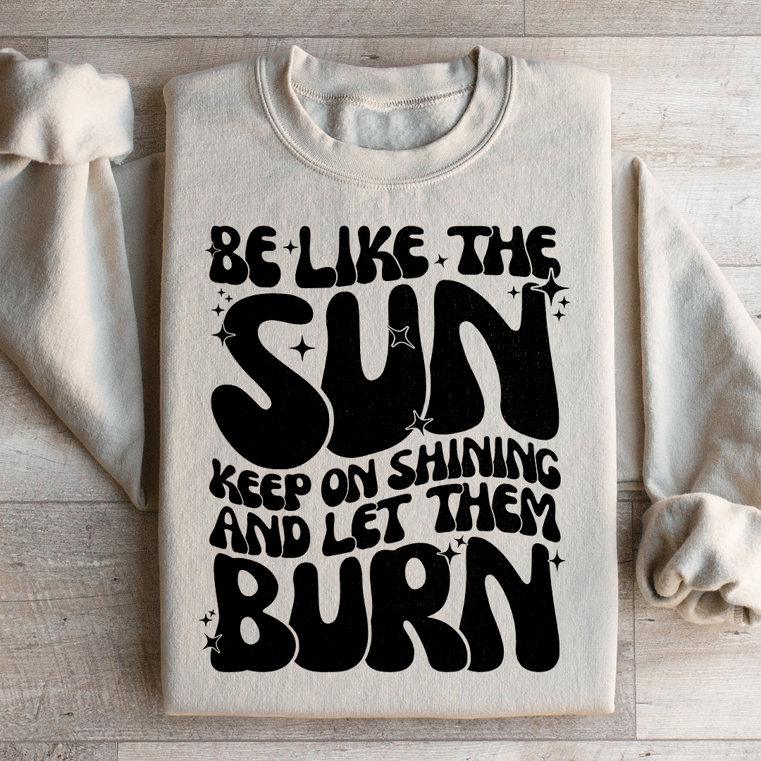 A cozy hoodie featuring the phrase 'Be Like The Sun Keep On Shining And Let Them Burn', designed by top artists, showcasing vibrant colors and a stylish fit.