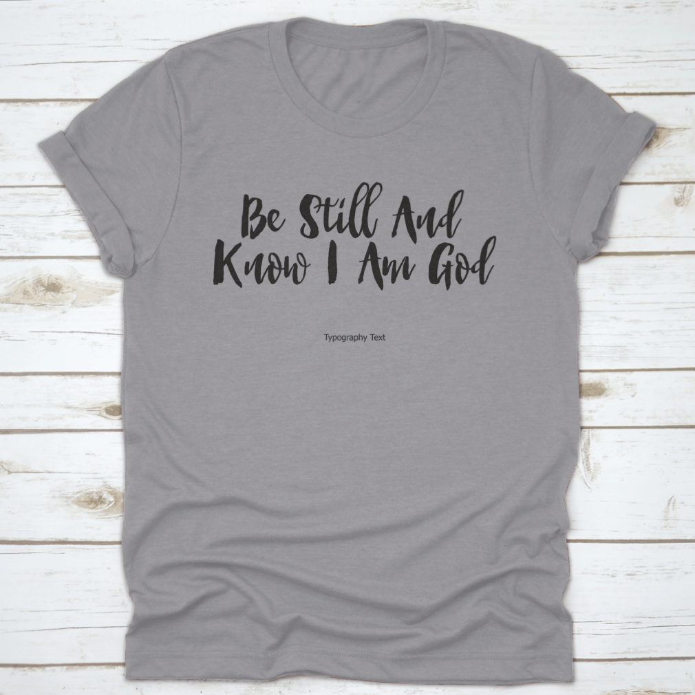 A comfortable T-shirt featuring the bold typography quote 'Be Still And Know I Am God', showcasing its inspirational design and quality fabric.