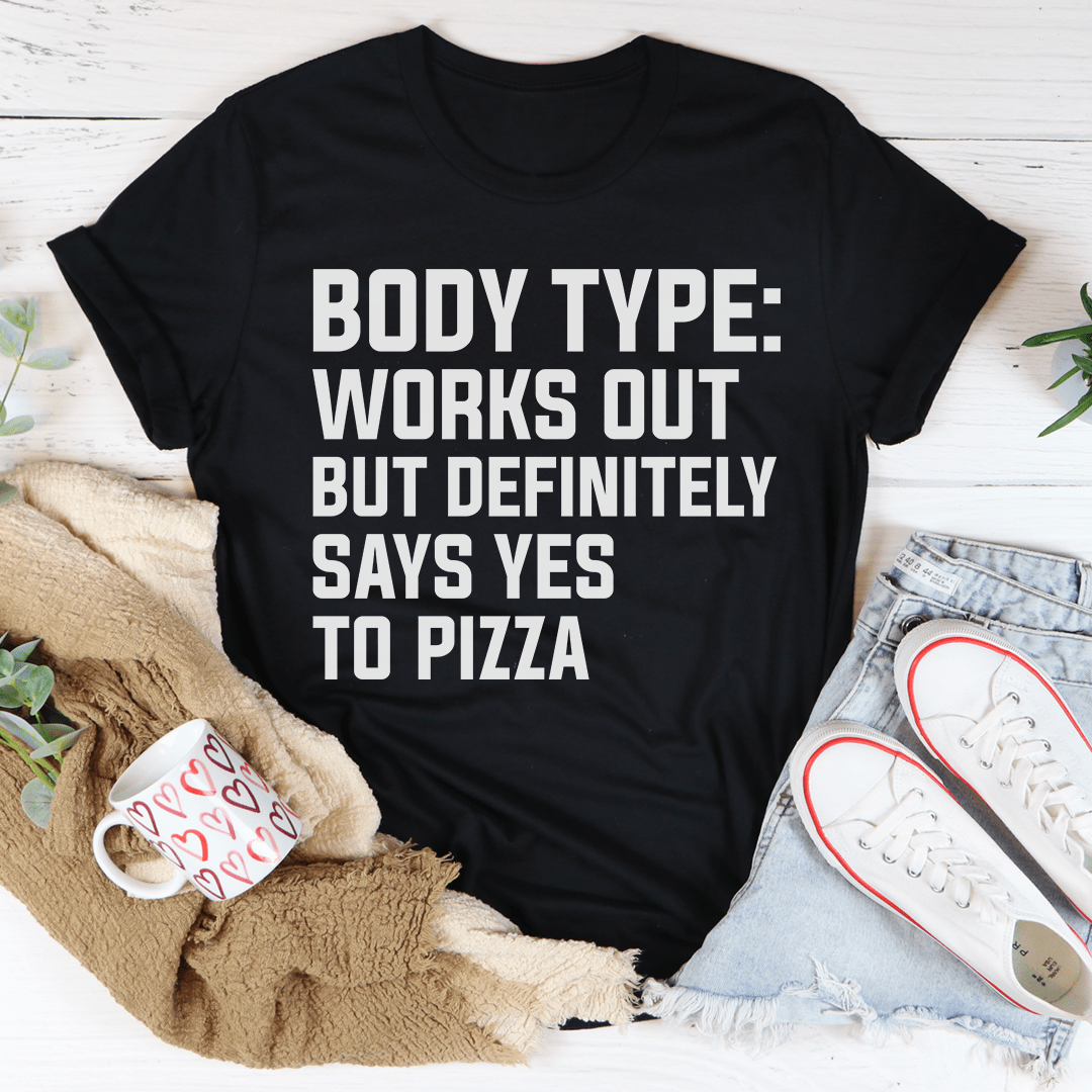 A comfortable and stylish t-shirt featuring the phrase 'Body Type Works Out But Definitely Says Yes To Pizza' in a playful design.