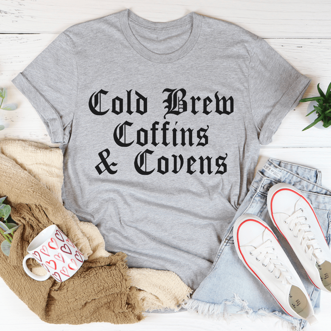 Cold Brew Coffins & Covens Tee featuring a spooky Halloween design, made from 100% soft cotton, perfect for festive celebrations.