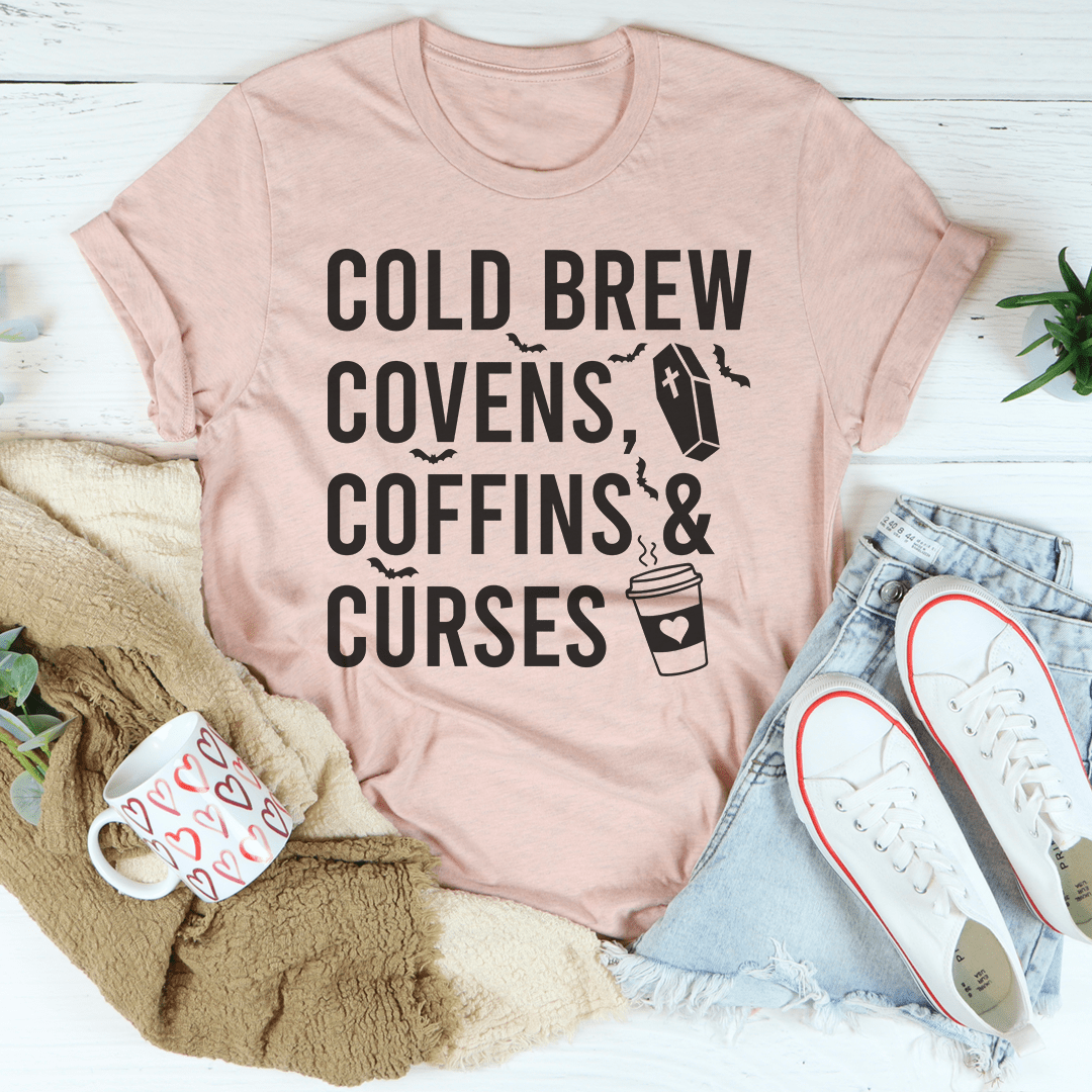 Cold Brew Covens Coffins Curses Tee featuring a spooky Halloween design on soft cotton fabric.