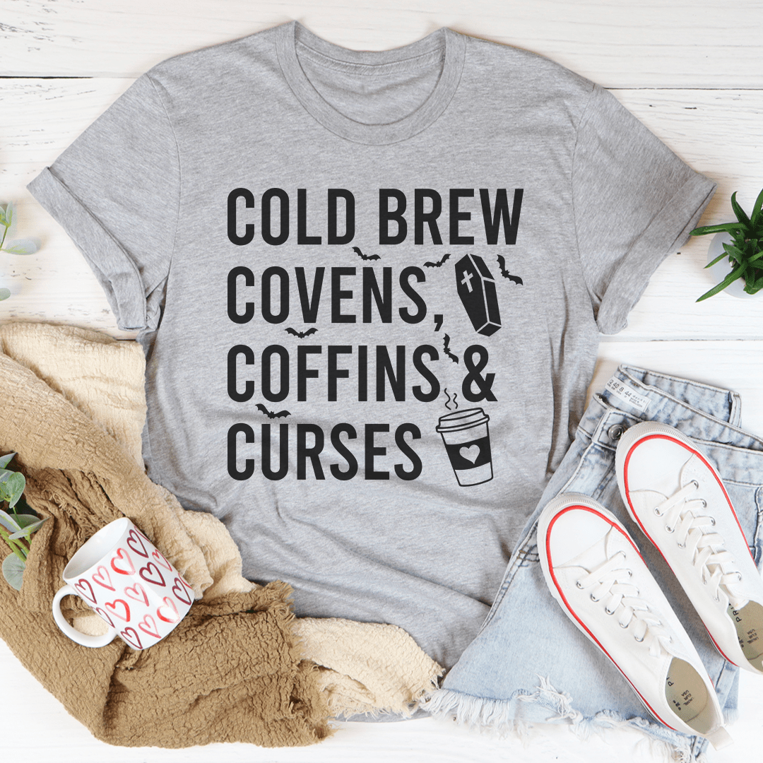 Cold Brew Covens Coffins Curses Tee featuring a spooky Halloween design on soft cotton fabric.