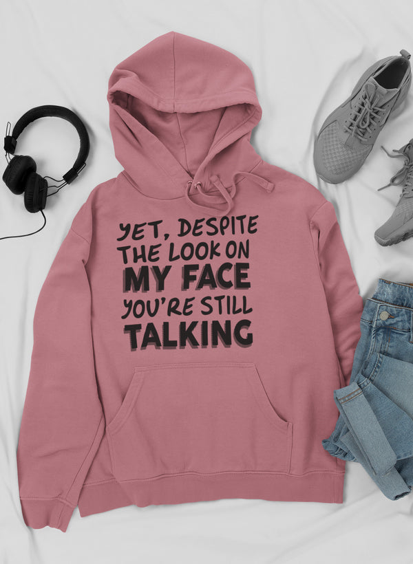 A stylish hoodie featuring the phrase 'Despite The Look On My Face You're Still Talking', designed by top artists, showcasing a cozy fleece material.