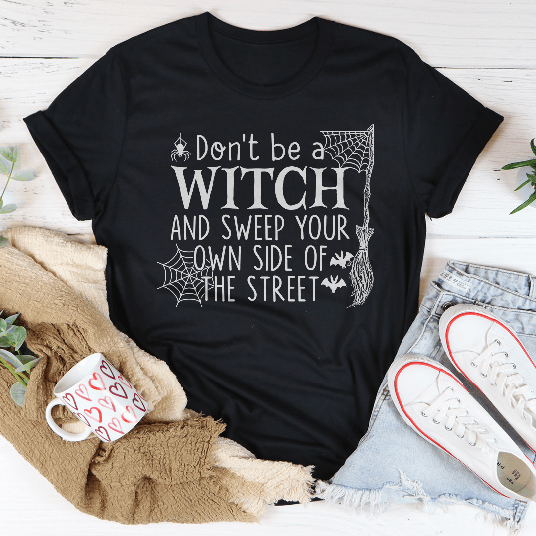 A comfortable Halloween tee featuring the phrase 'Don't Be A Witch & Sweep Your Own Side Of The Street' printed in vibrant colors on soft cotton fabric.