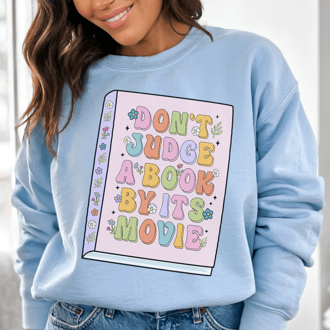 A cozy 'Don't Judge A Book' hoodie featuring unique artistic designs, made from a cotton/poly fleece blend for warmth and comfort.