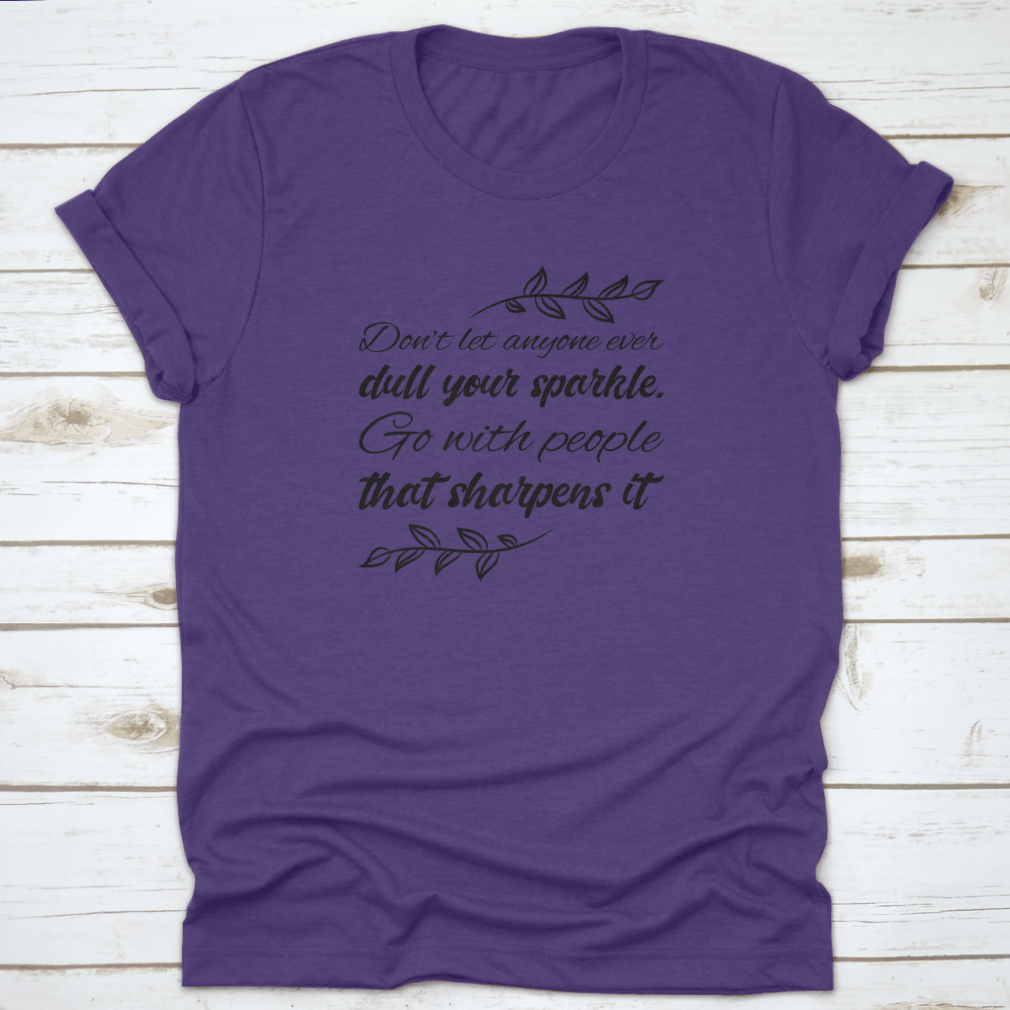 A stylish t-shirt featuring the quote 'Don’t Let Anyone Dull Your Sparkle' in a vibrant design, made from 100% cotton.