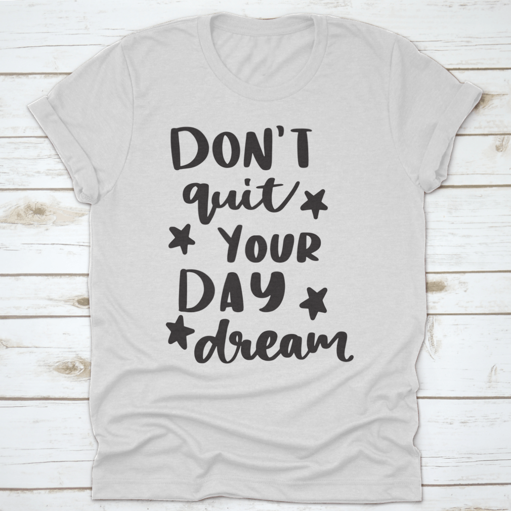 A motivational calligraphy shirt featuring the phrase 'Don't Quit Your Daydream' in stylish lettering, made from soft cotton fabric.