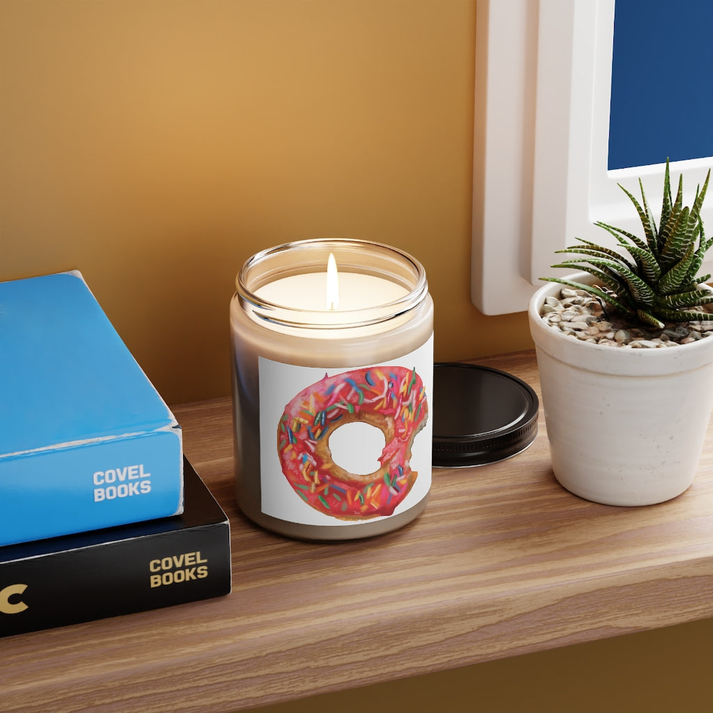 A beautifully hand-poured Donut Scented Candle in a glass container, featuring a permanent adhesive label and available in Cinnamon Stick and Vanilla fragrances.