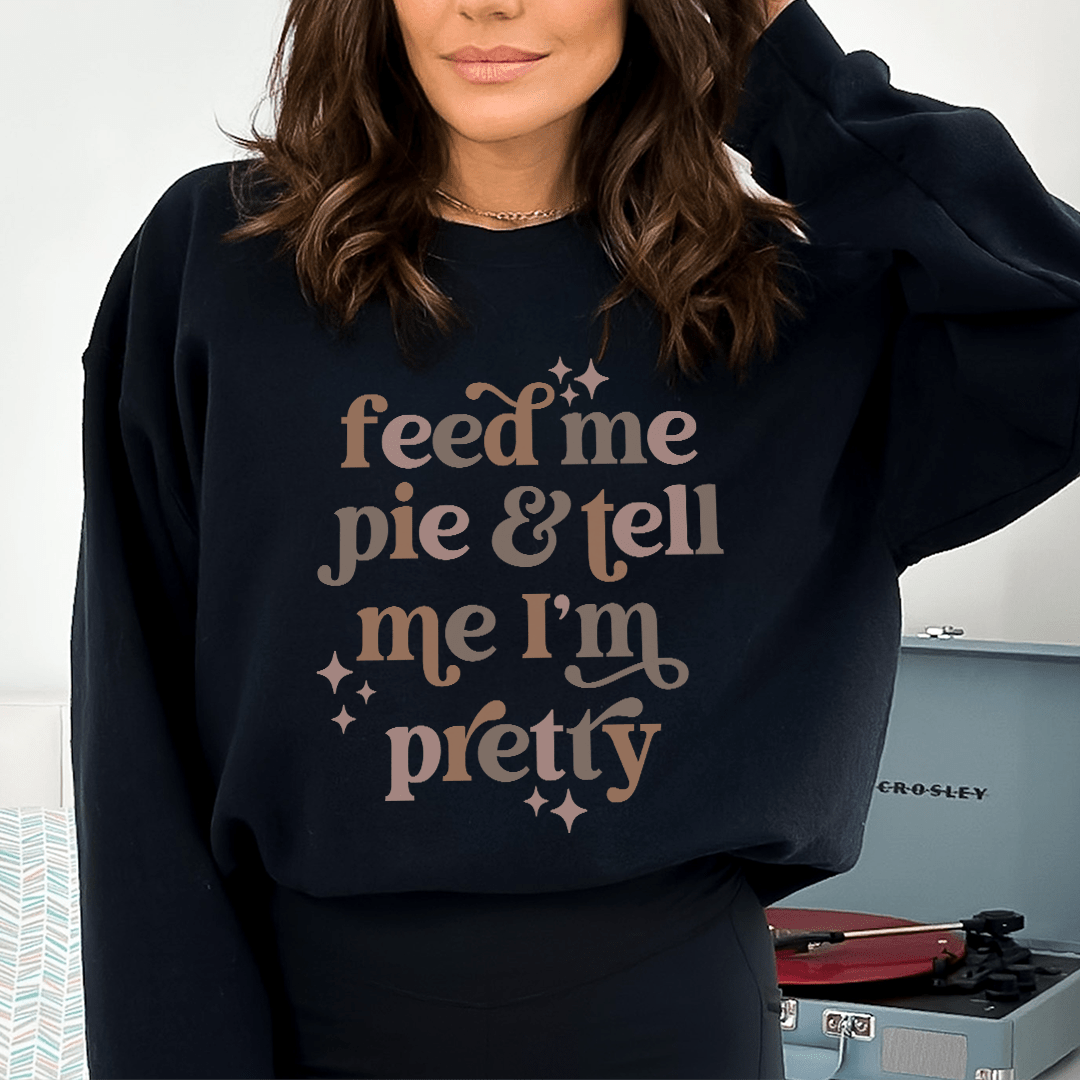 Cozy sweatshirt featuring the phrase 'Feed Me Pie And Tell Me I'm Pretty', designed by top artists, made from cotton/poly fleece blend.