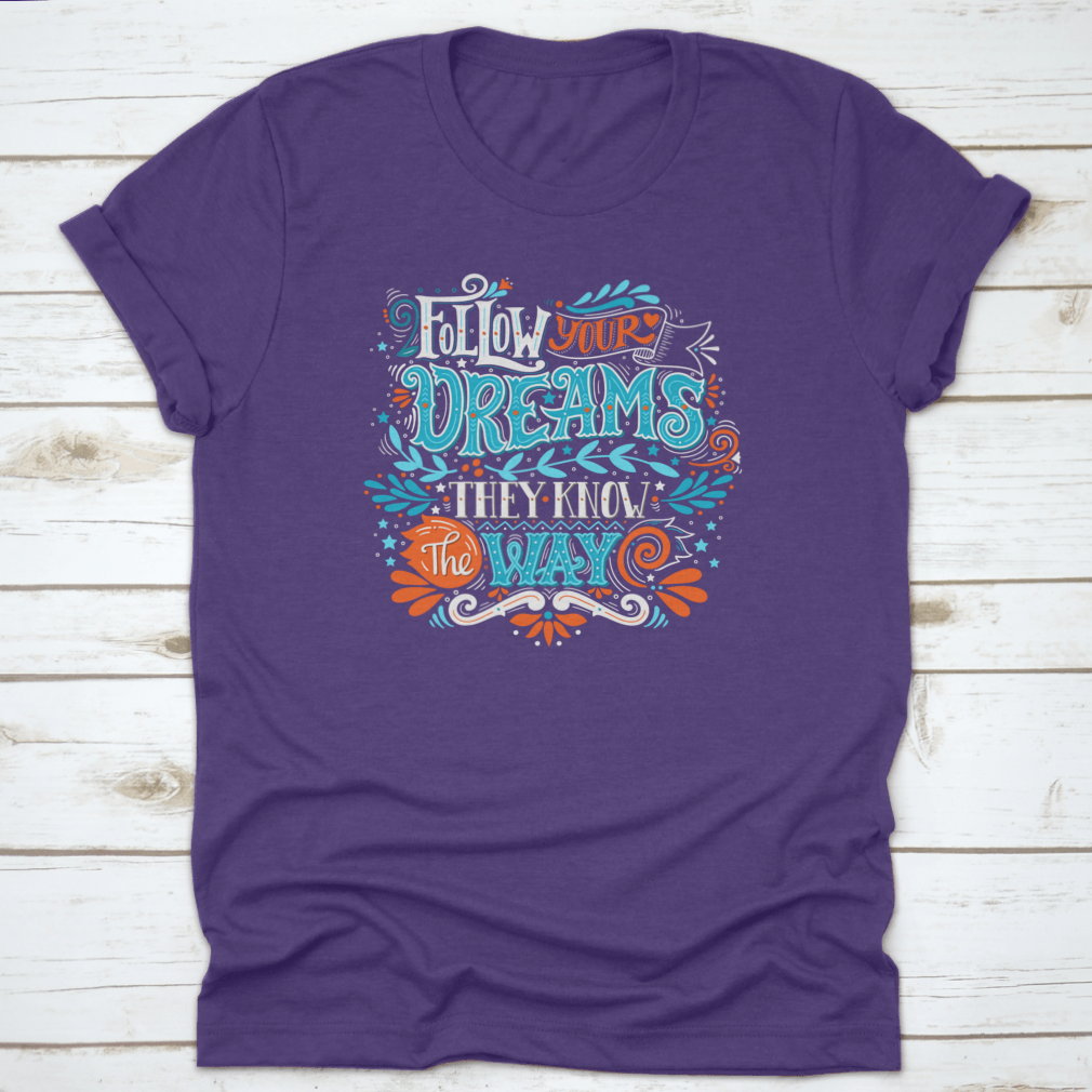 A hand-drawn inspirational quote T-shirt featuring the phrase 'Follow Your Dreams. They Know The Way' in a stylish design.