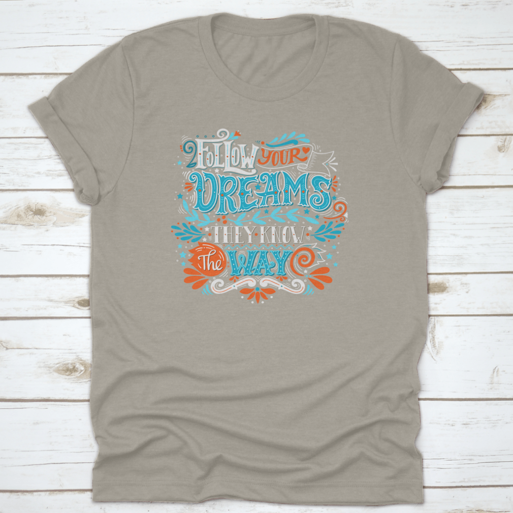 A hand-drawn inspirational quote T-shirt featuring the phrase 'Follow Your Dreams. They Know The Way' in a stylish design.