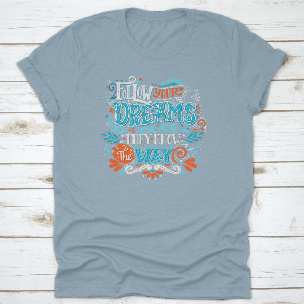 A hand-drawn inspirational quote T-shirt featuring the phrase 'Follow Your Dreams. They Know The Way' in a stylish design.