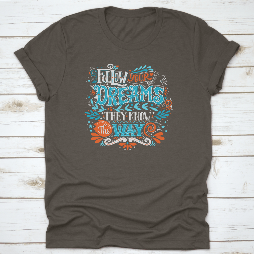 A hand-drawn inspirational quote T-shirt featuring the phrase 'Follow Your Dreams. They Know The Way' in a stylish design.