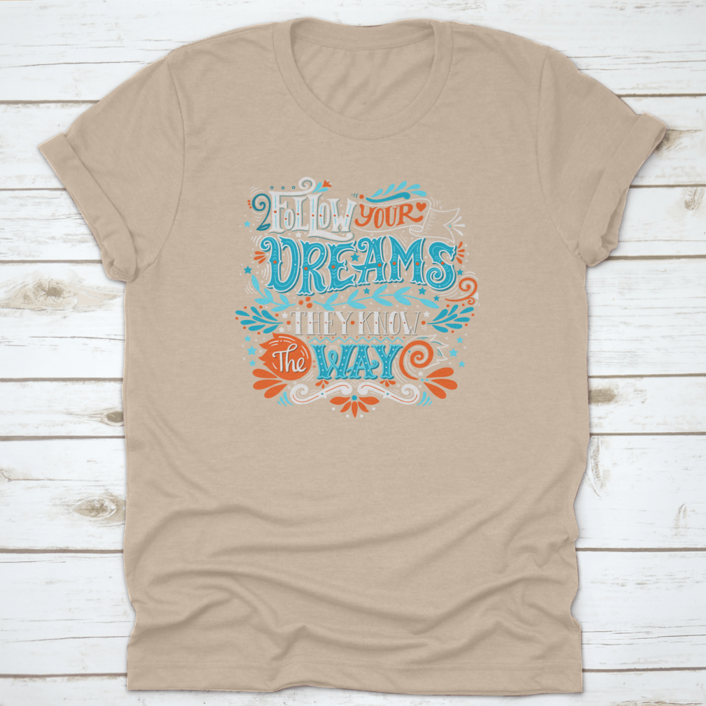 A hand-drawn inspirational quote T-shirt featuring the phrase 'Follow Your Dreams. They Know The Way' in a stylish design.