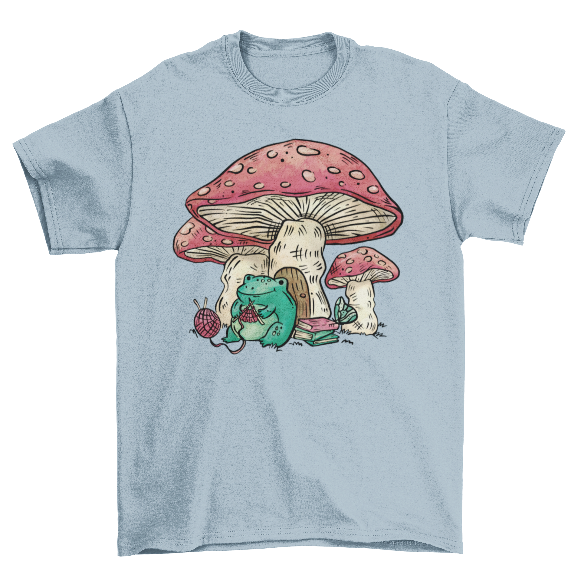 A whimsical t-shirt featuring a cheerful frog knitting next to a colorful mushroom house.
