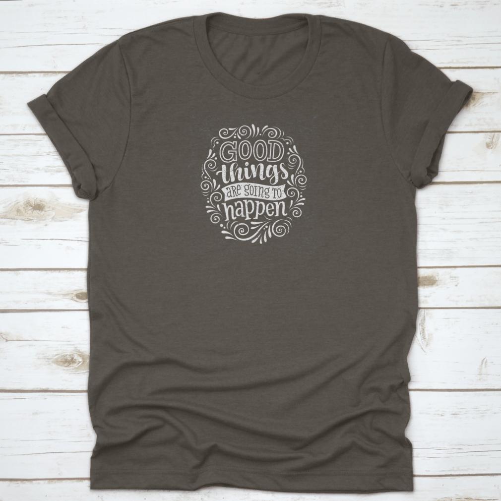 A motivational quote t-shirt featuring the phrase 'Good Things Are Going To Happen', made from 100% cotton, displayed on a neutral background.