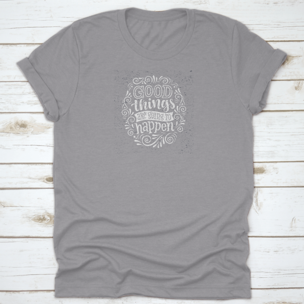 A motivational quote t-shirt featuring the phrase 'Good Things Are Going To Happen', made from 100% cotton, displayed on a neutral background.