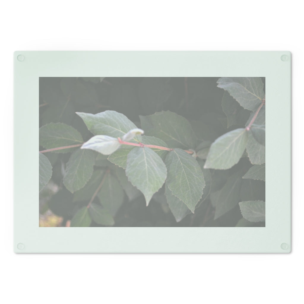 A stylish Green Leaves Cutting Board made of tempered glass, featuring a vibrant green leaves design and four rubber dots for stability.
