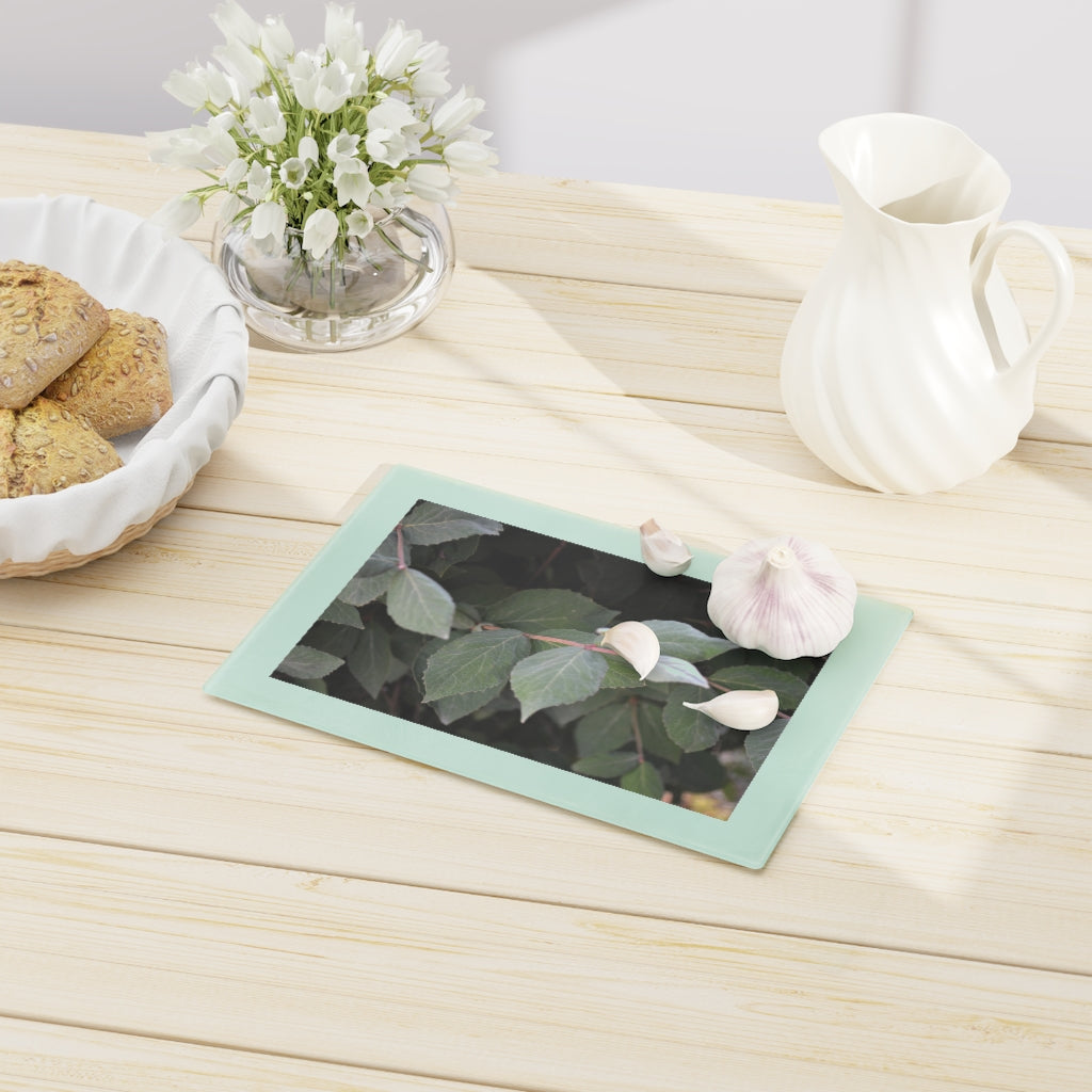 A stylish Green Leaves Cutting Board made of tempered glass, featuring a vibrant green leaves design and four rubber dots for stability.