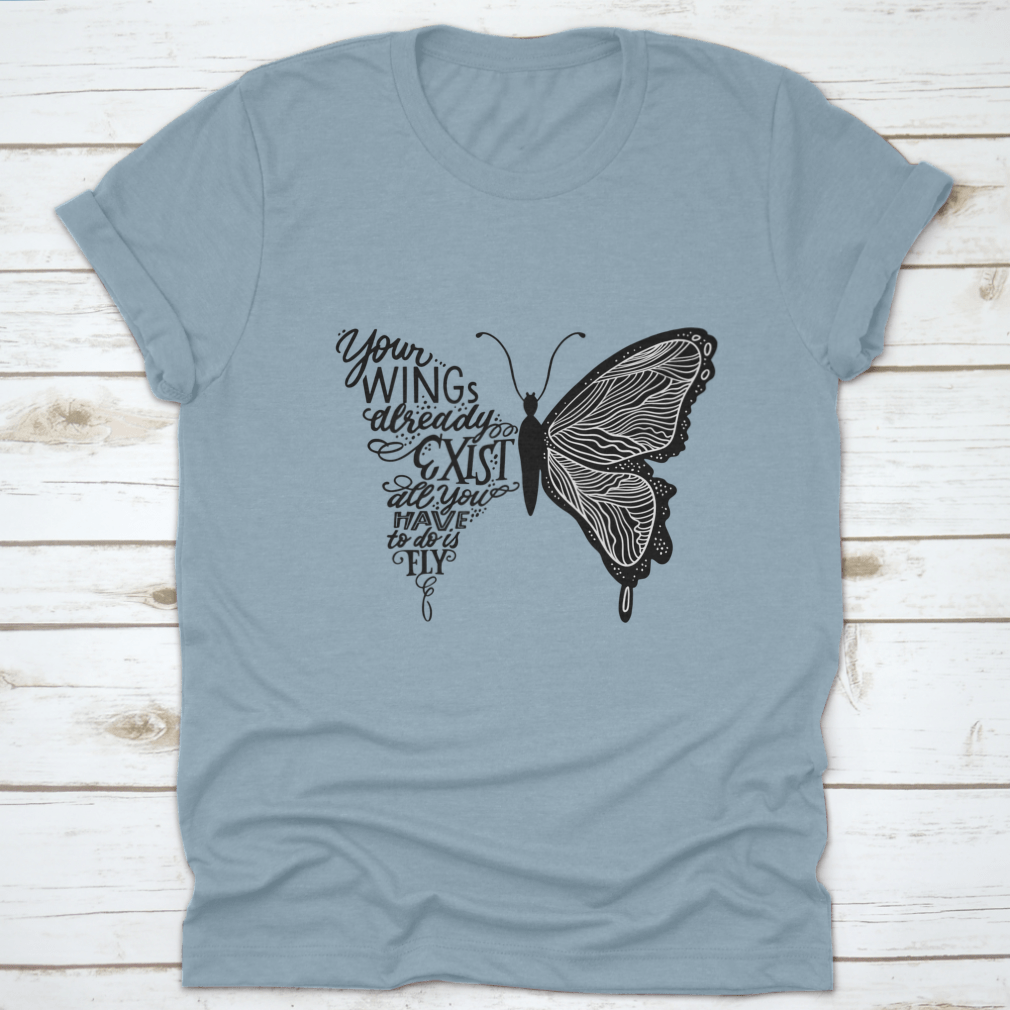 A stylish t-shirt featuring hand lettering in a butterfly silhouette design, showcasing the phrase 'Your Wings Already Exists All' on a soft fabric.