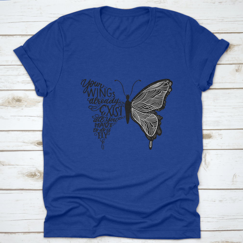A stylish t-shirt featuring hand lettering in a butterfly silhouette design, showcasing the phrase 'Your Wings Already Exists All' on a soft fabric.