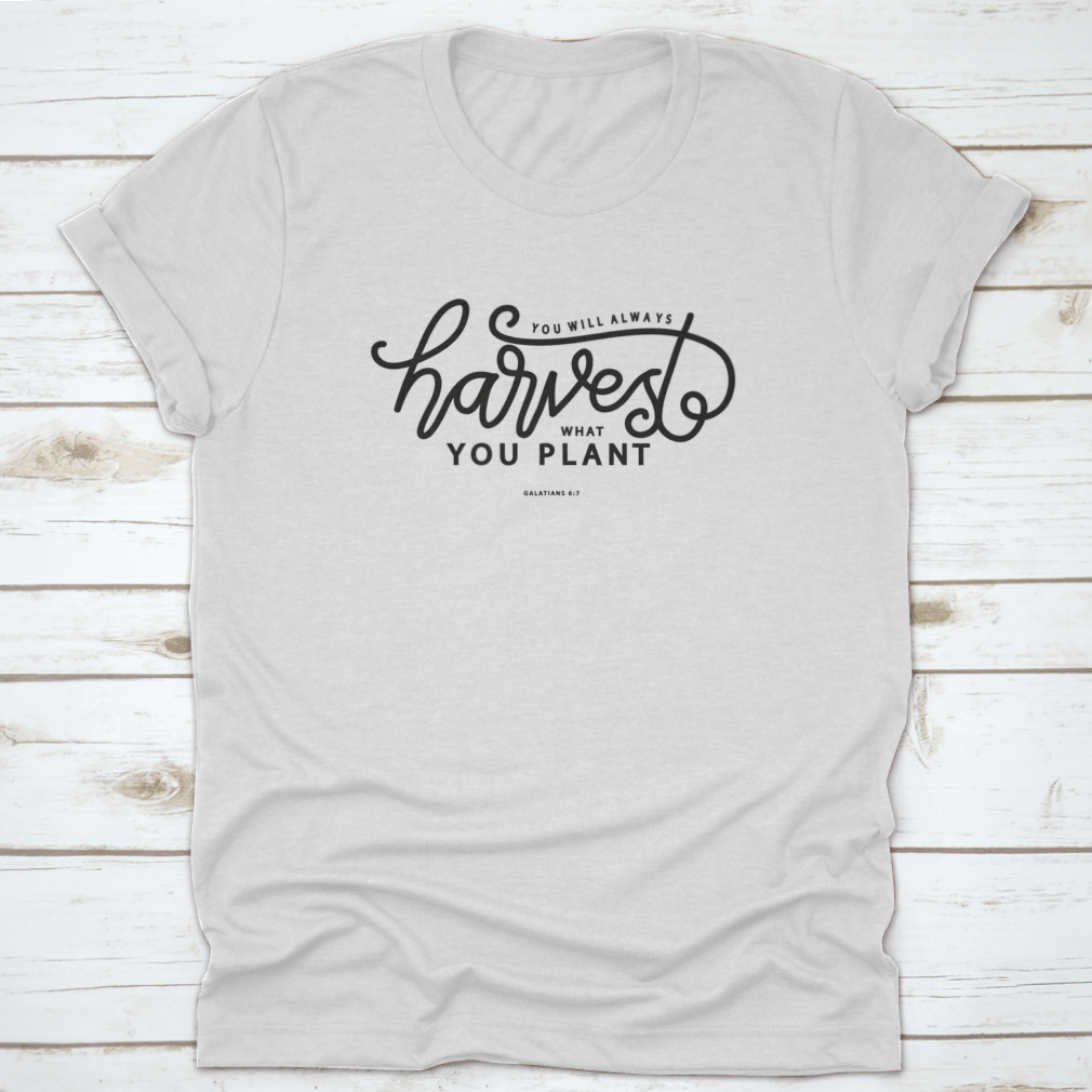 A stylish white t-shirt featuring hand lettering that says 'You Will Always Harvest What You Plant', showcasing its unique design and quality fabric.