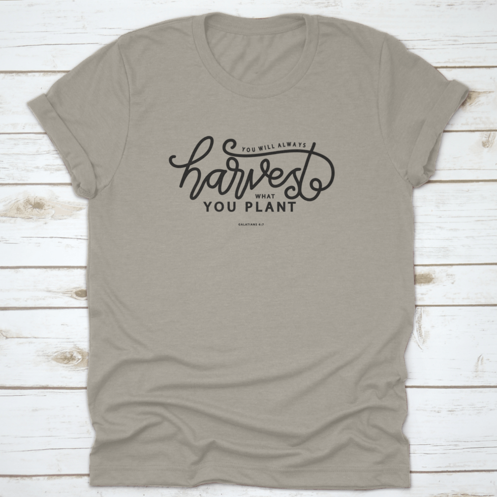 A stylish white t-shirt featuring hand lettering that says 'You Will Always Harvest What You Plant', showcasing its unique design and quality fabric.