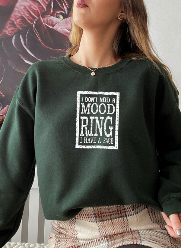 A cozy sweatshirt featuring the phrase 'I Don't Need A Mood Ring I HAVE A FACE' in a stylish font, perfect for casual wear.