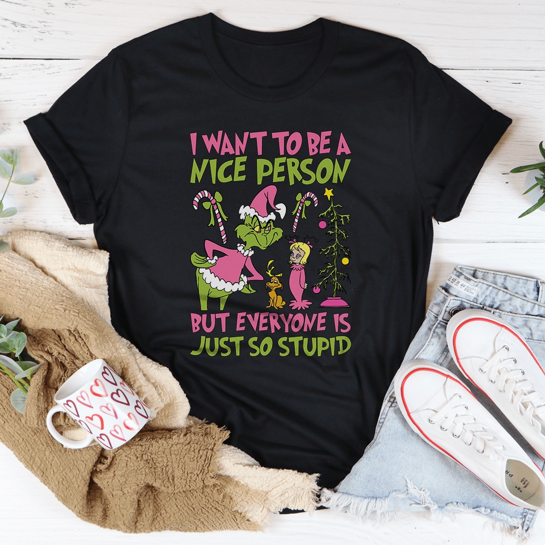 A festive tee featuring the phrase 'I Want To Be A Nice Person But Everyone Is Just So Stupid', made from 100% soft cotton, perfect for the holiday season.