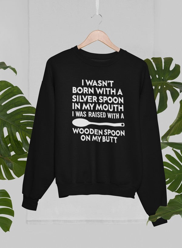A cozy sweatshirt featuring the phrase 'I Wasn't Born with a Silver Spoon in My Mouth', designed by top artists, showcasing a stylish and comfortable fit.