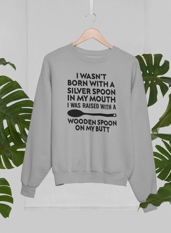 A cozy sweatshirt featuring the phrase 'I Wasn't Born with a Silver Spoon in My Mouth', designed by top artists, showcasing a stylish and comfortable fit.