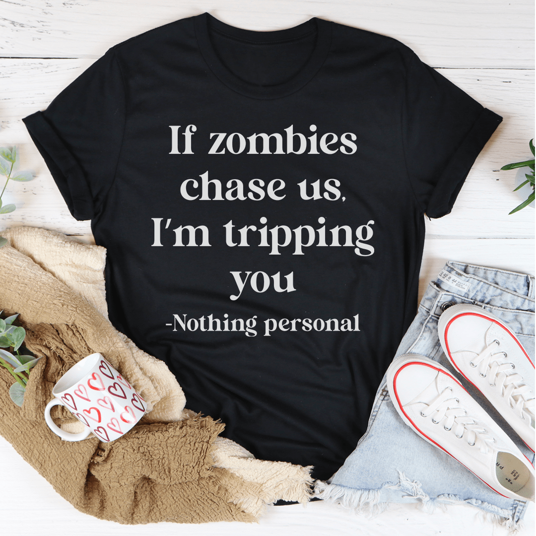 A humorous t-shirt featuring the phrase 'If Zombies Chase Us I'm Tripping You' printed on soft cotton fabric, perfect for zombie lovers.