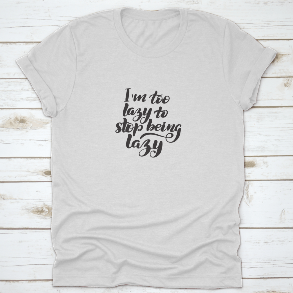 A comfortable cotton T-shirt featuring inspirational handwritten brush lettering that reads 'I'M Too Lazy To Stop Being', perfect for casual wear.