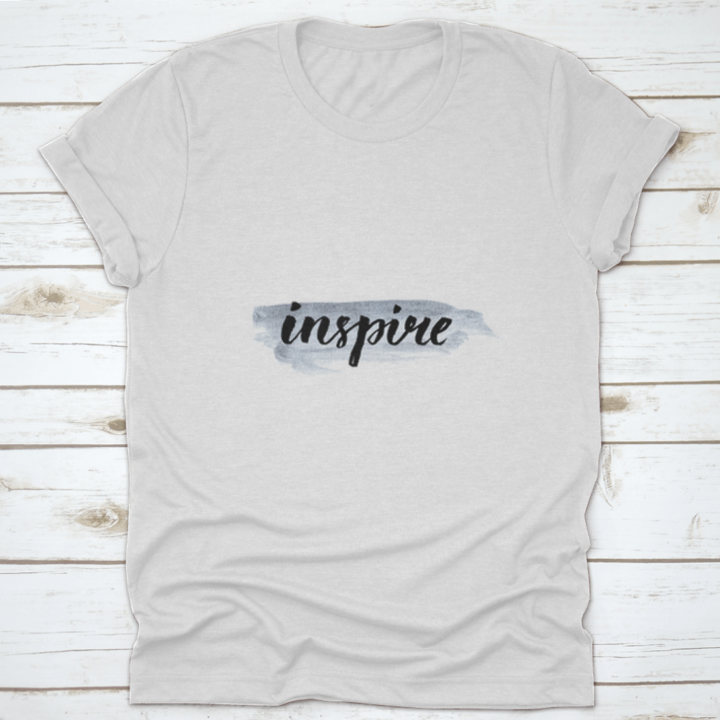Inspire Calligraphy Word Handwritten on Silver Paint, showcasing elegant lettering on a stylish fabric background.