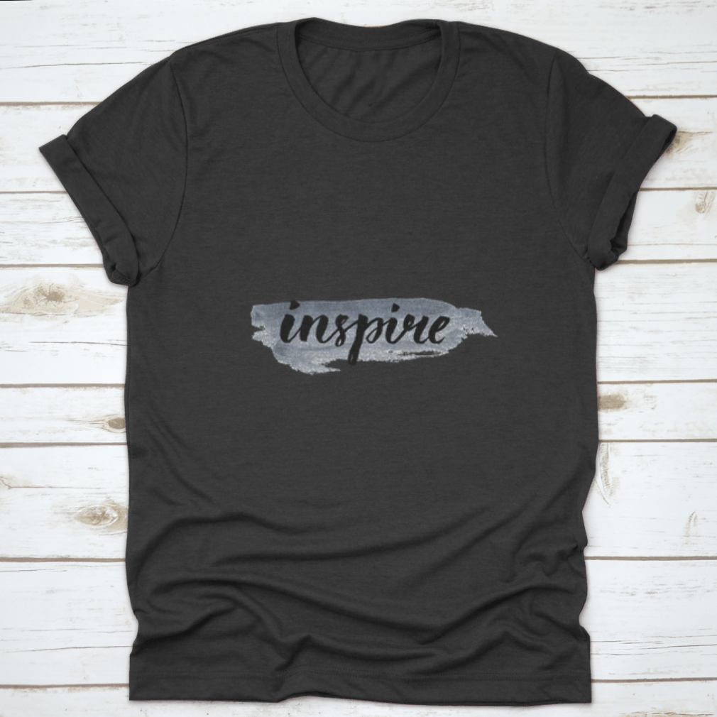 Inspire Calligraphy Word Handwritten on Silver Paint, showcasing elegant lettering on a stylish fabric background.