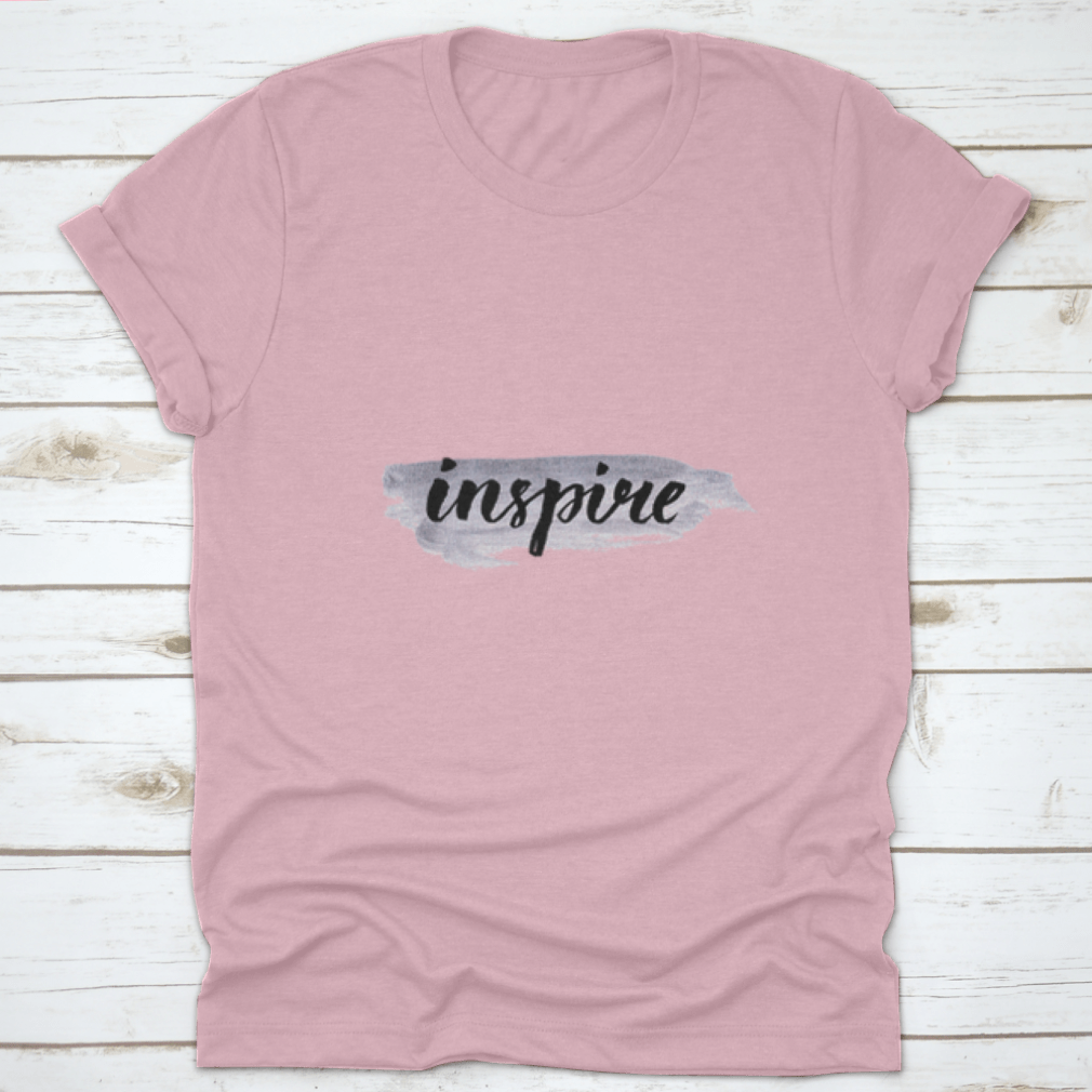 Inspire Calligraphy Word Handwritten on Silver Paint, showcasing elegant lettering on a stylish fabric background.